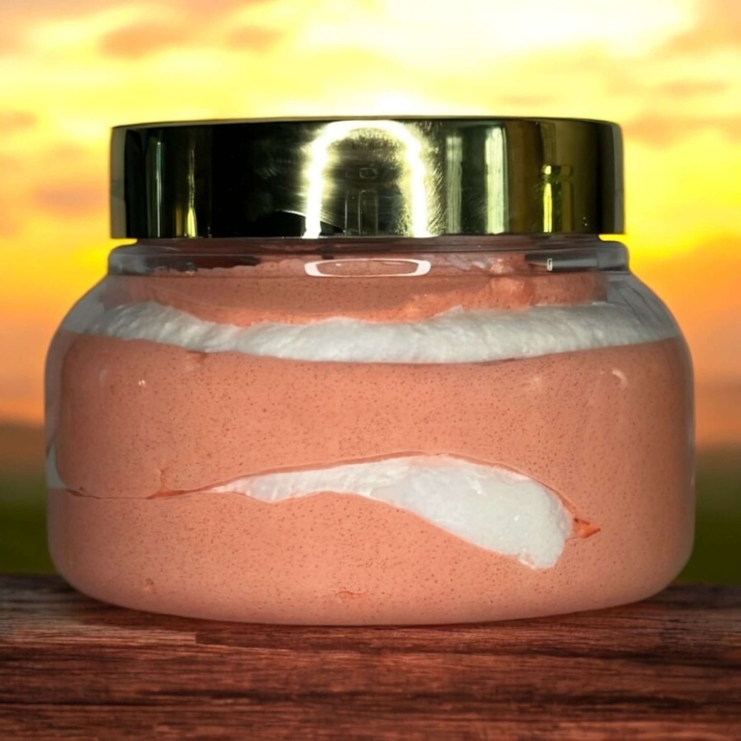 Foaming sugar scrub in a jar with a golden lid, depicting a soft pink and white texture, against a sunset background.